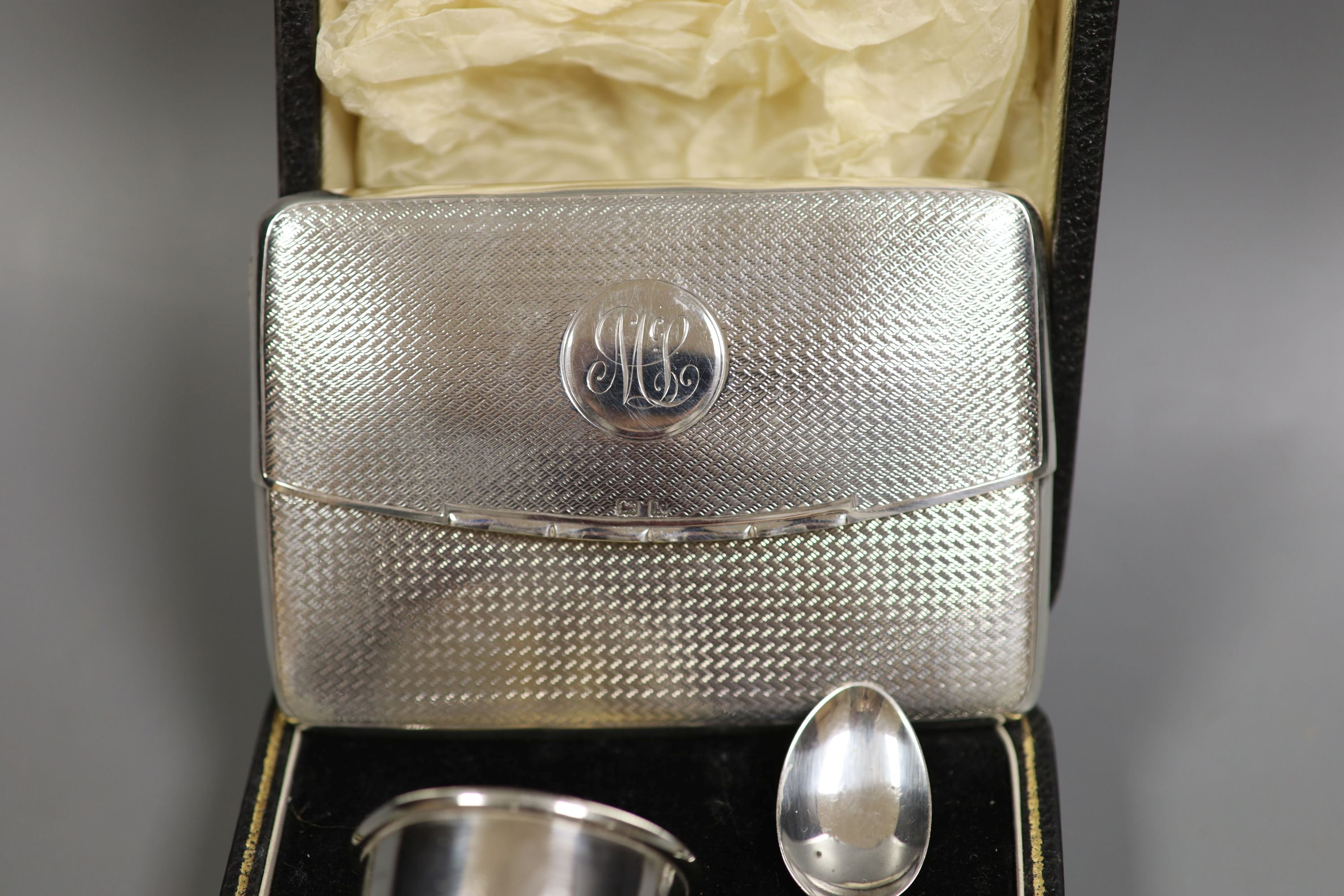 An Edwardian engine tuned silver 'envelope' card case, Birmingham, 1909, 10.4cm and a cased silver christening egg cup and spoon.